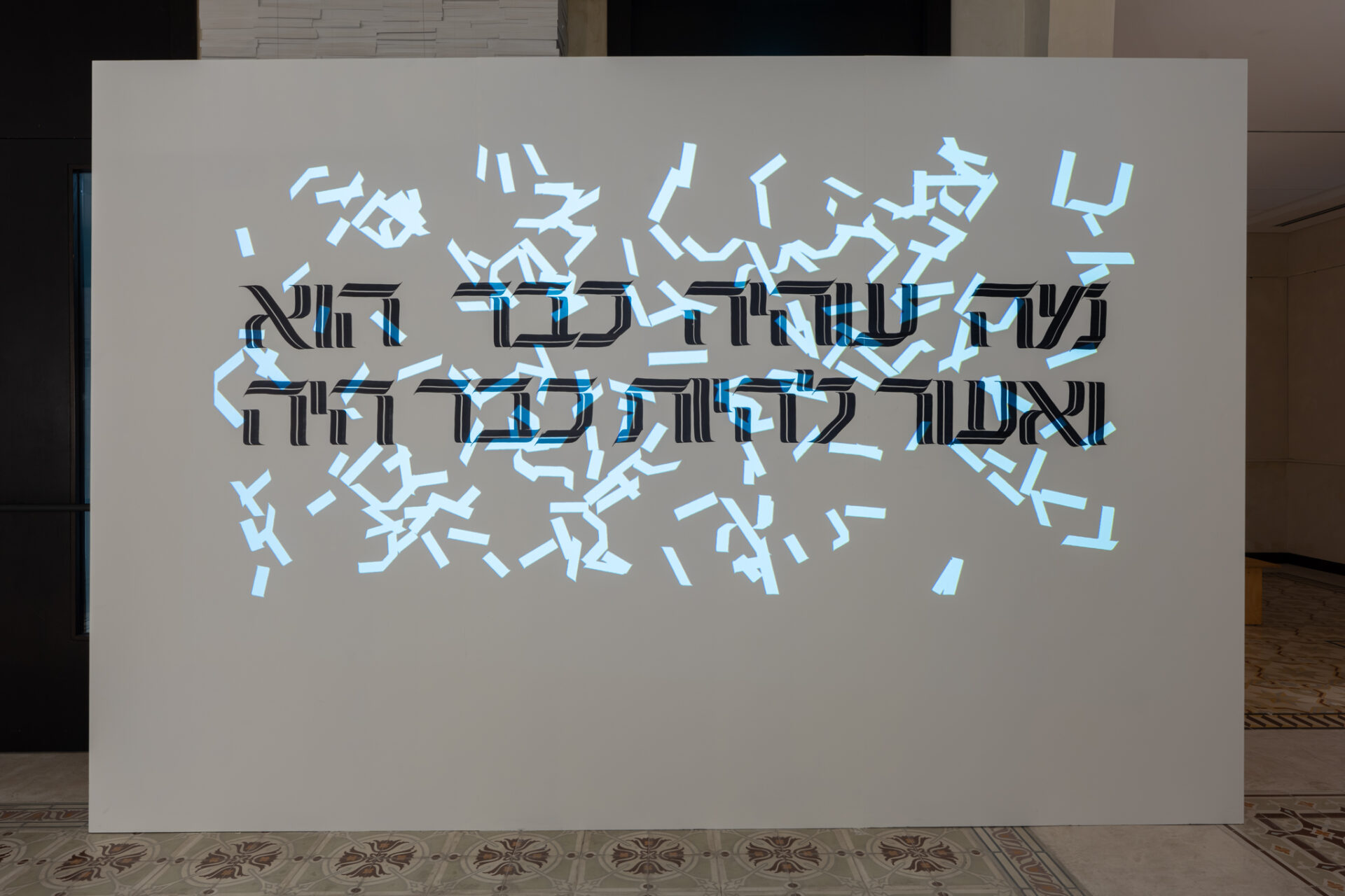 רותם פינקלשטיין –> נדב פיינר –> רון שחר –> מיכל קרניאלי –> רוני בן פורת –> דוד מוטהדה –> שלי פיחה<br />
חיים מחדש, 2026, דיגיטל ואקריליק על קיר, מידות משתנות<br />
פונט המקור בעבודה: 